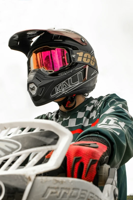 a man in a checkered jacket and red helmet holding up a white and black motorcycle