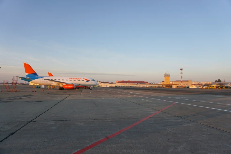 two orange and white airplanes sit on the runway