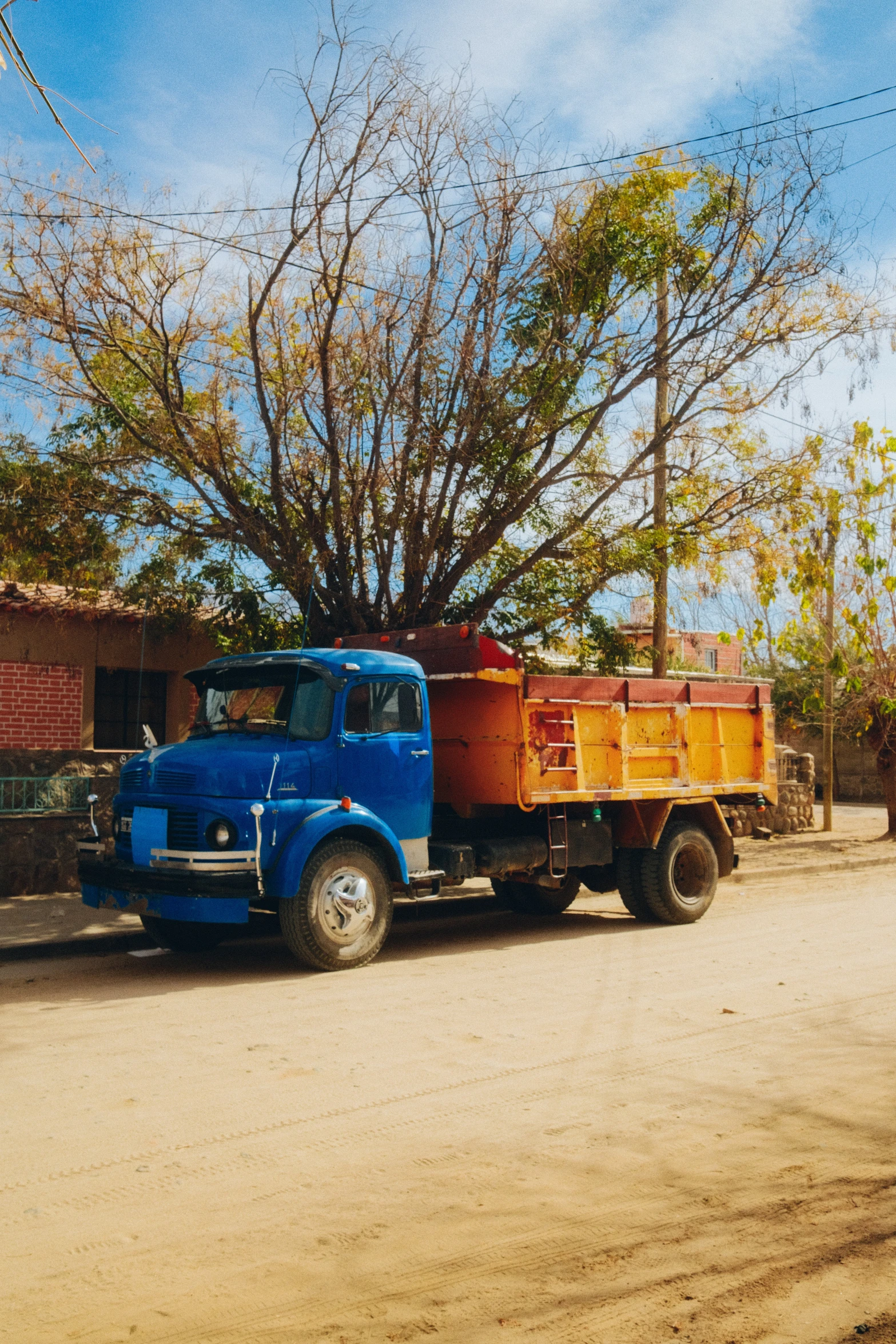 a blue dump truck traveling down a road past trees