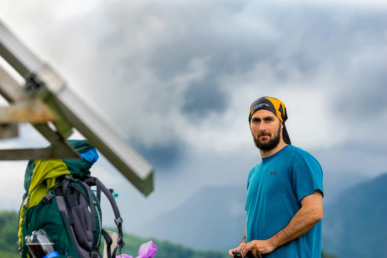 a man with a hat on stands near a mountain