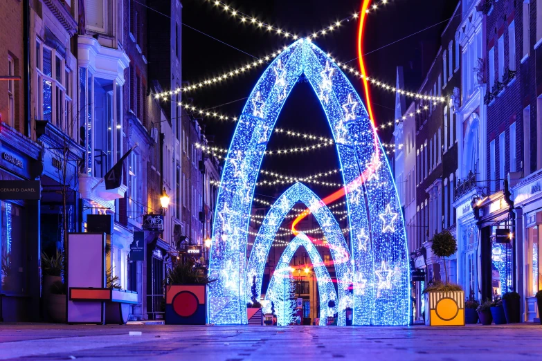 a street that has lit up blue christmas lights in the front of it