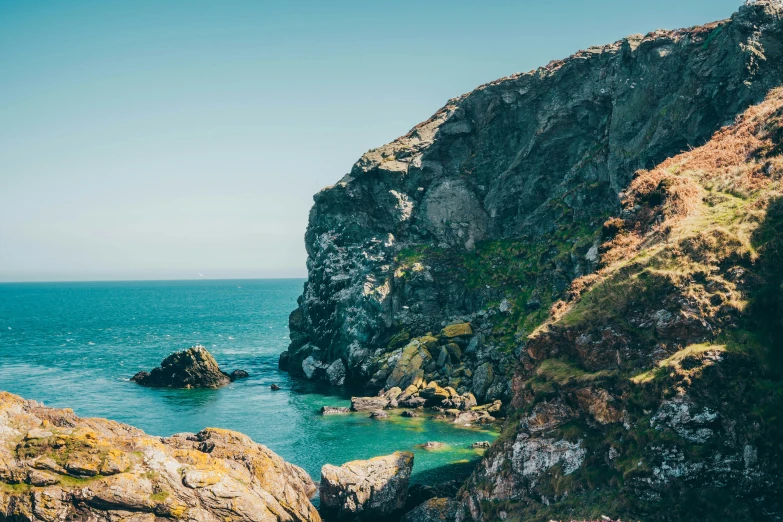 a body of water near some rocks by the ocean