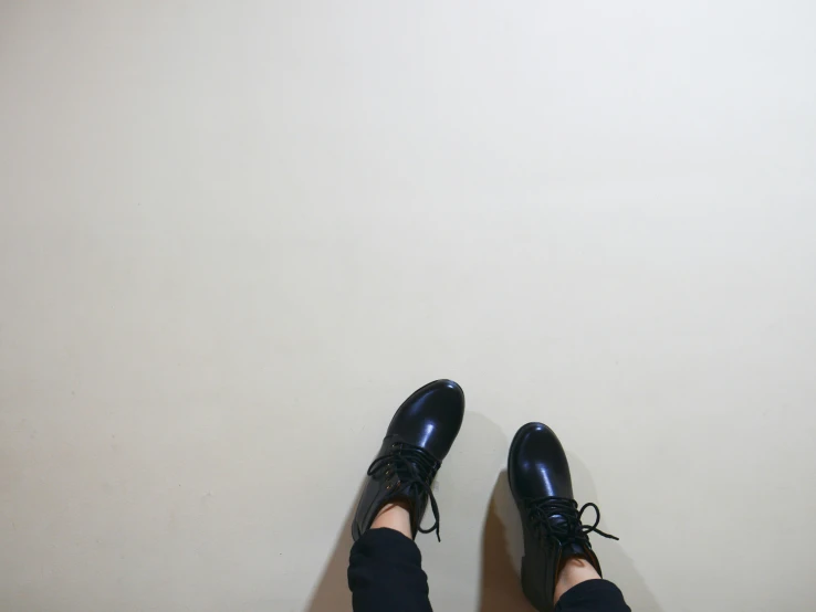 a person in black shoes standing in a room