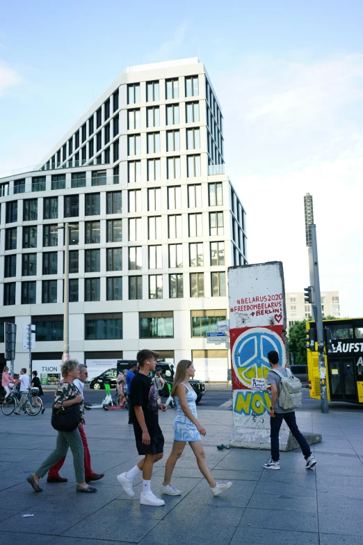 people walk past a large city building with a mural