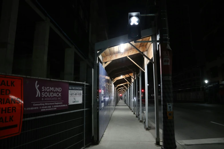 a long covered sidewalk with a sign and some signs on the side