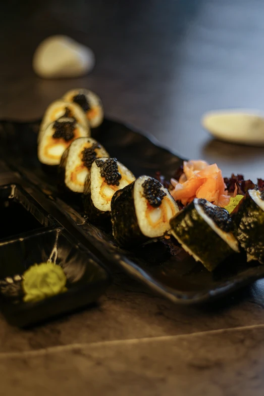 several kinds of sushi are arranged on a black plate