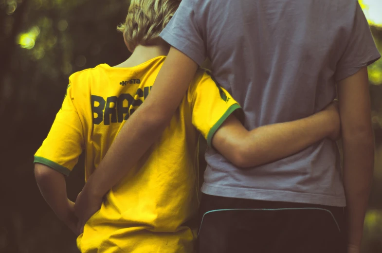 two children standing next to each other, one is wearing a yellow shirt