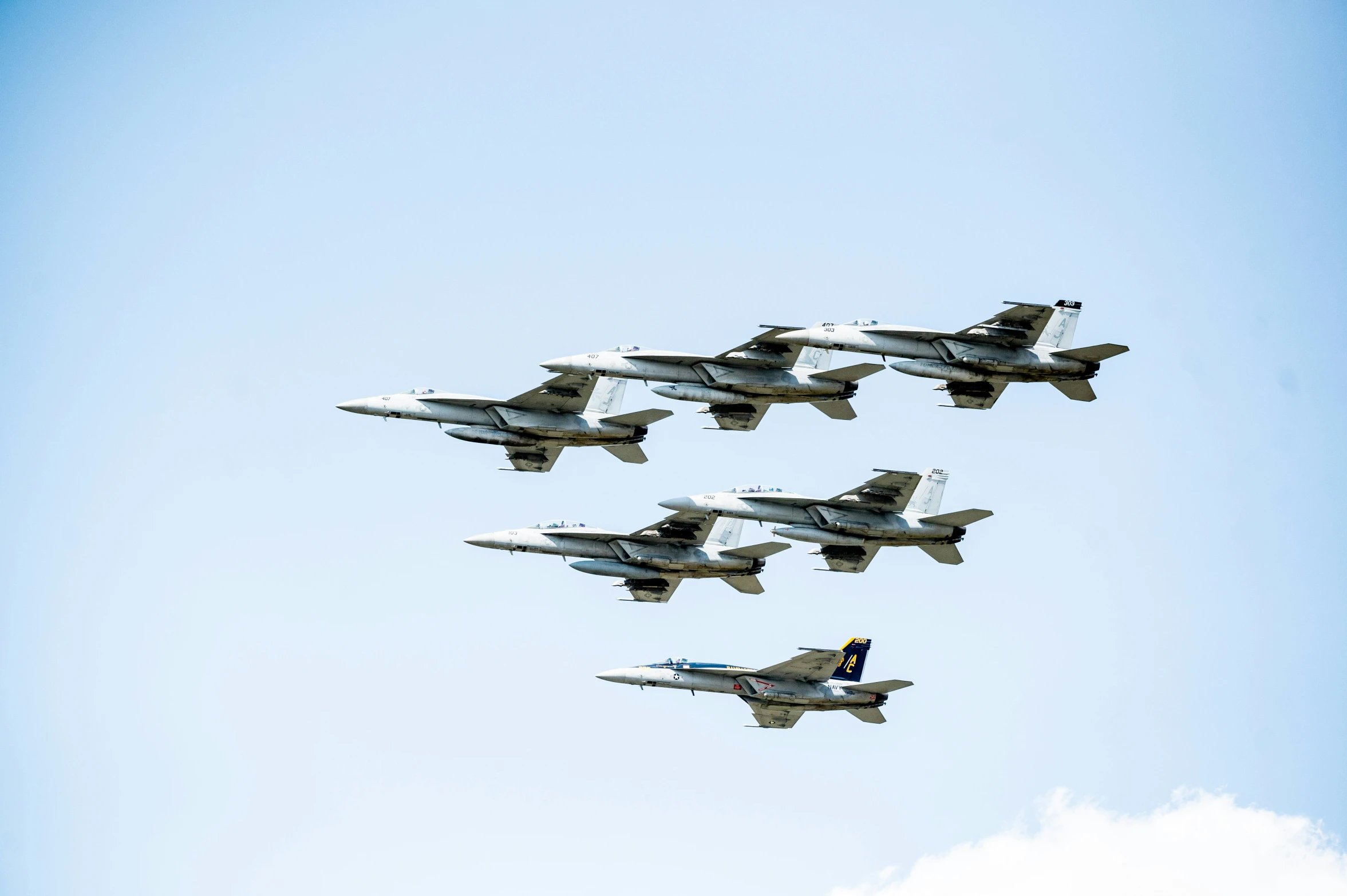 four jets fly through the sky with one following a group of other airplanes