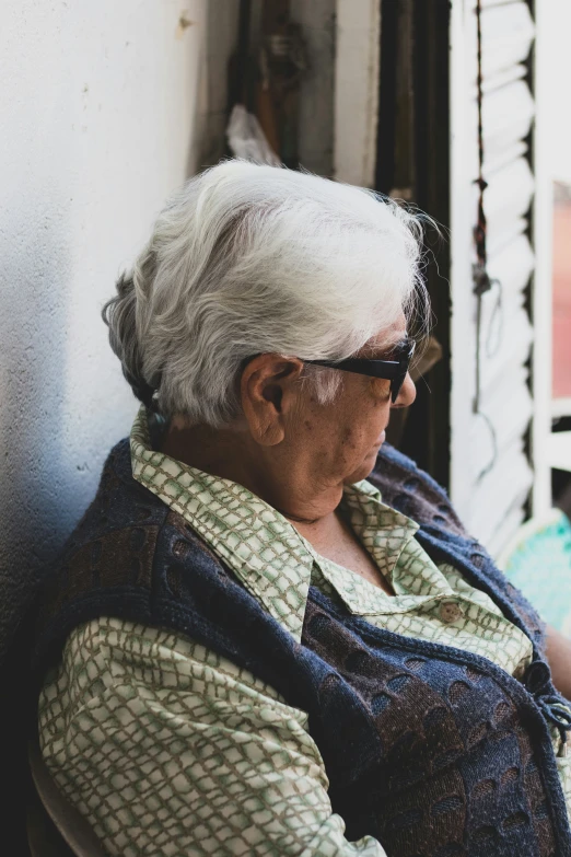 an old lady sitting by the window looking out of the window