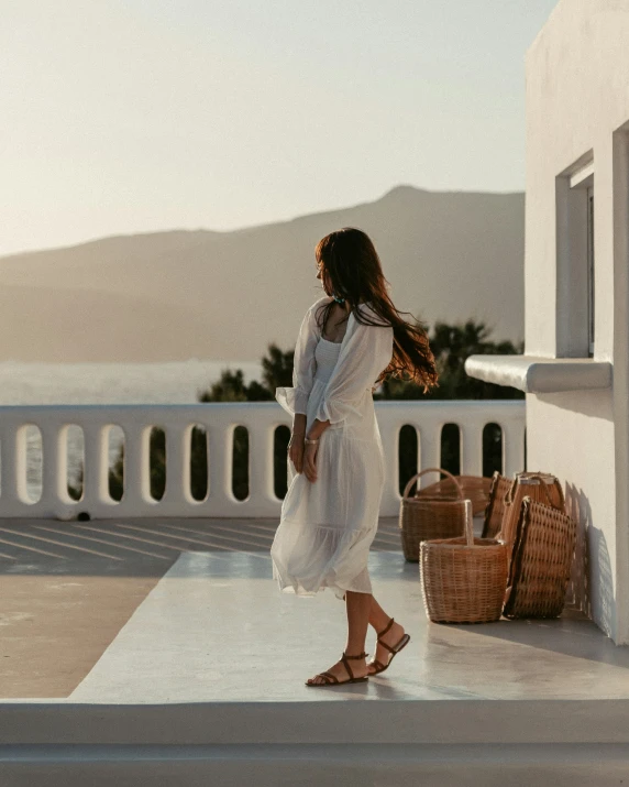 a woman stands on the outside steps of a balcony and looks away into the distance