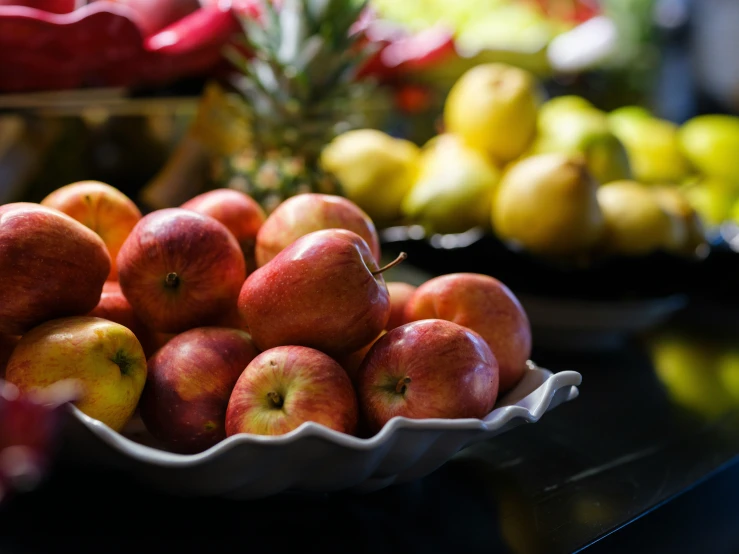 apples are sitting in a bowl with other fruit around them