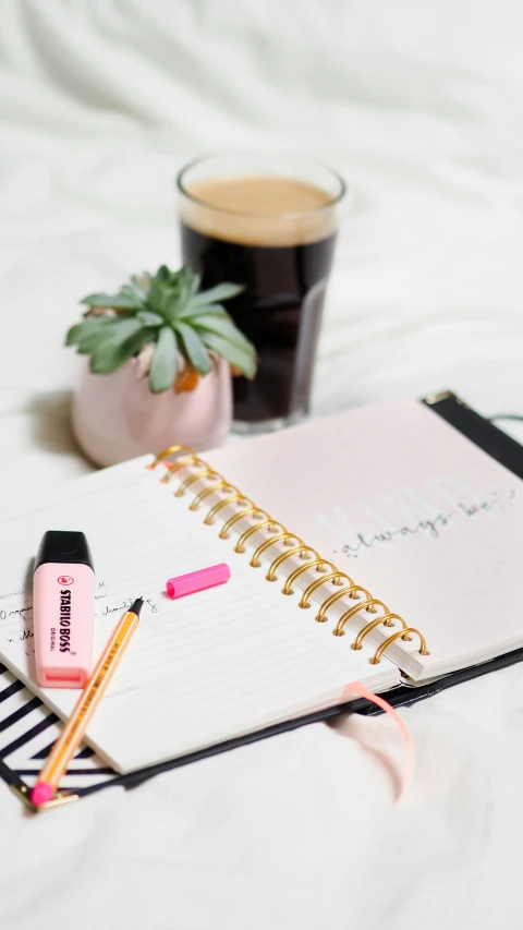 a black and white po with pens and notebook next to coffee