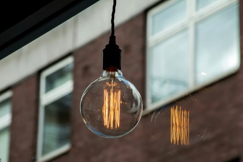 an old - fashioned lightbulb hanging off a brick building