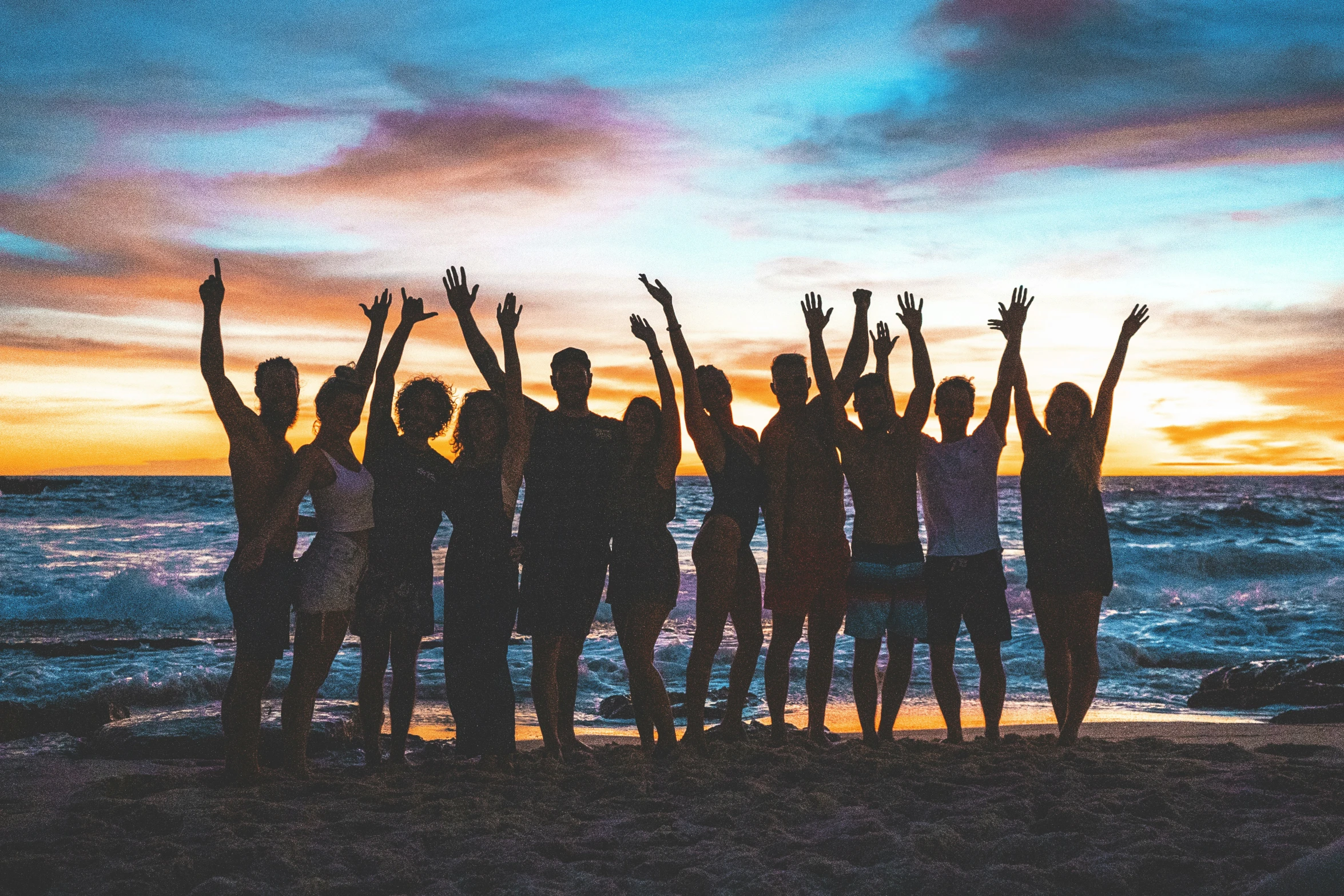 a group of people standing on top of a sandy beach