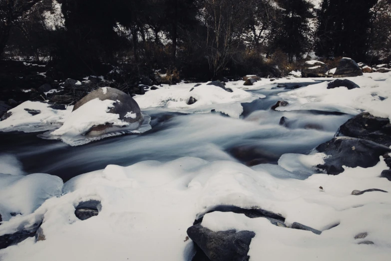 a snowy mountain stream that is surrounded by rocks