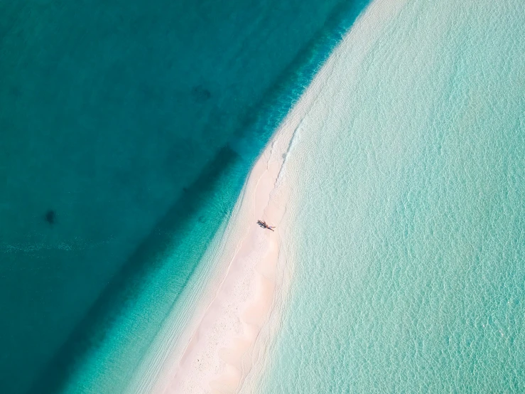 an overhead view of two people in water next to a beach