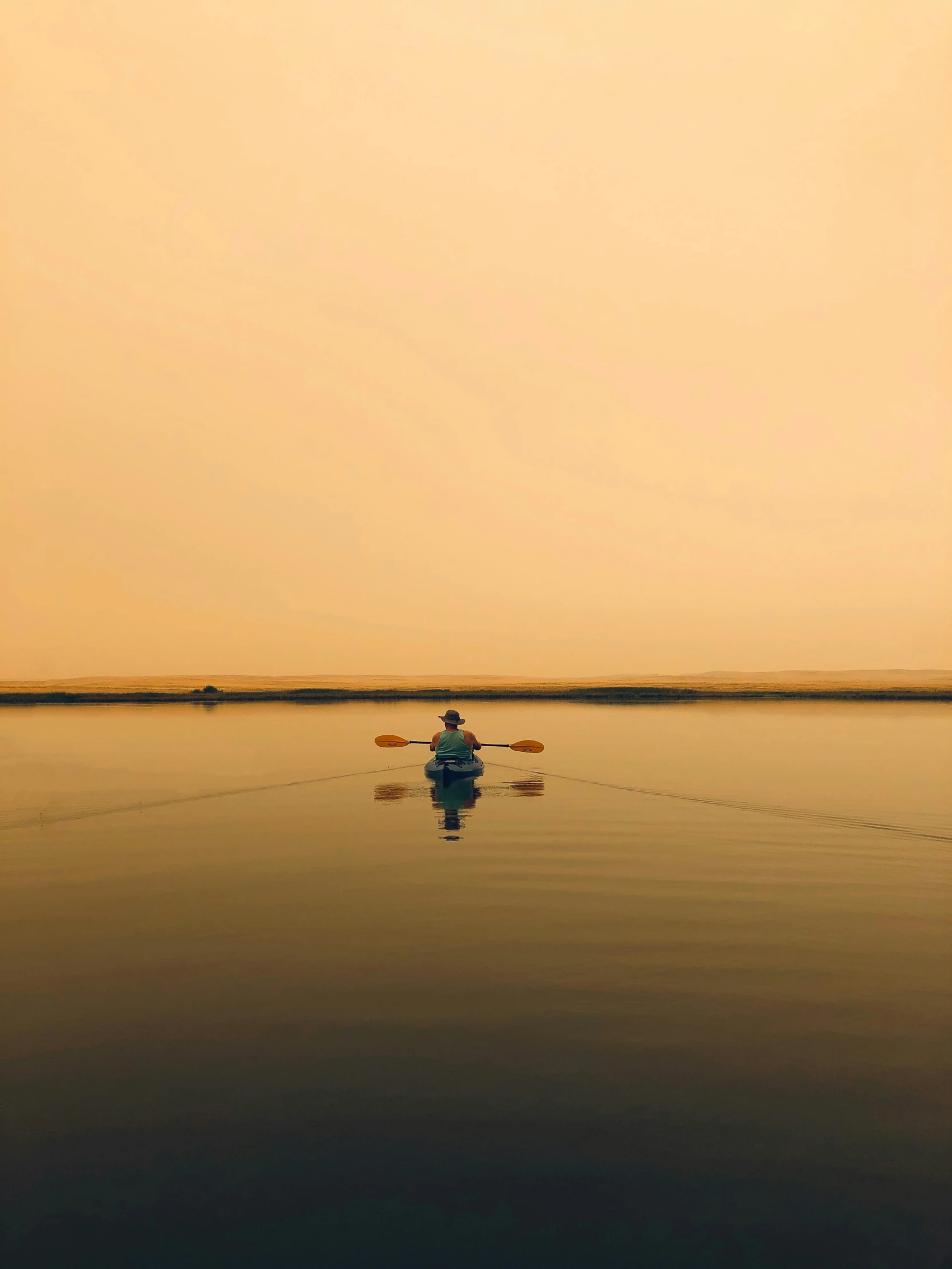 a small man in a kayak paddling alone across the water