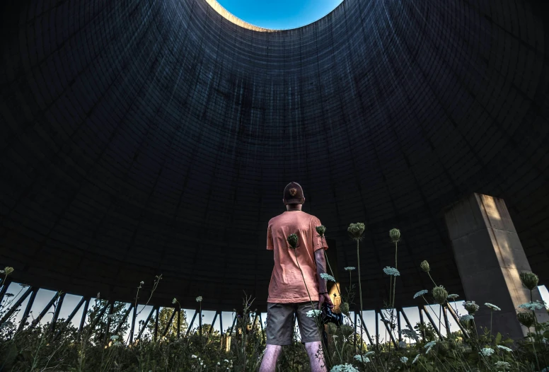 a man standing under a dome holding a skateboard