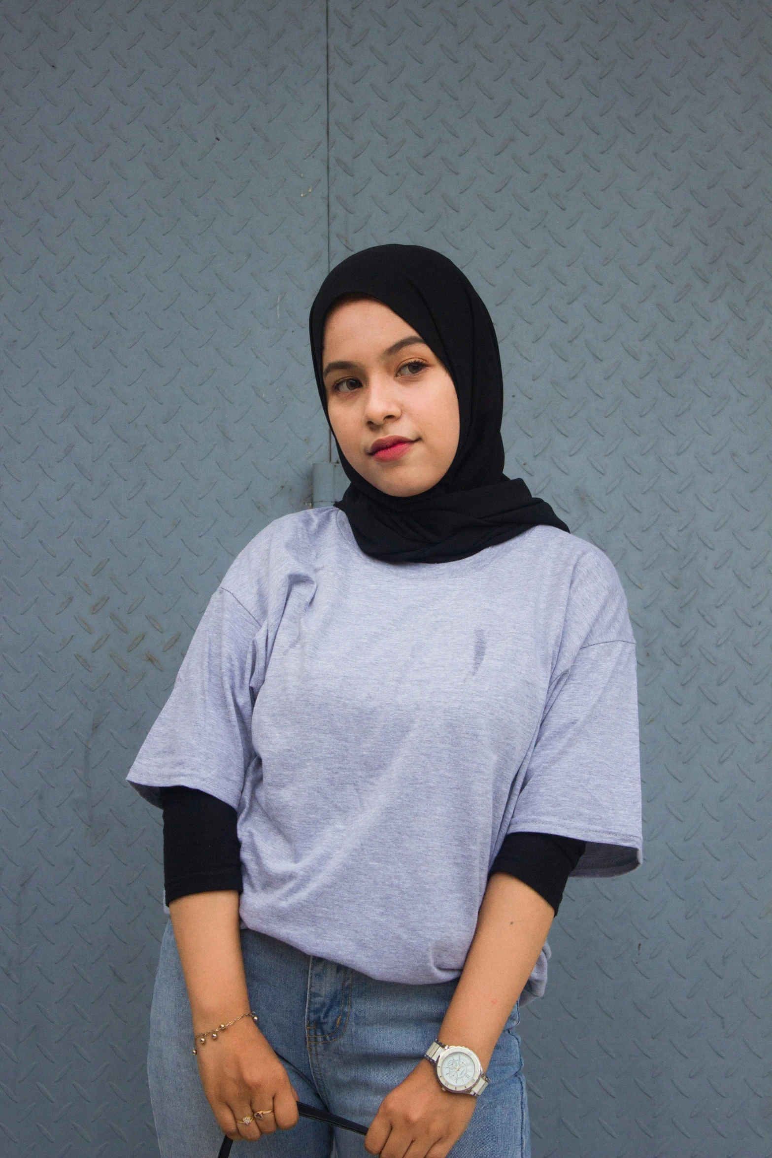 a woman in a hijab standing in front of a wall