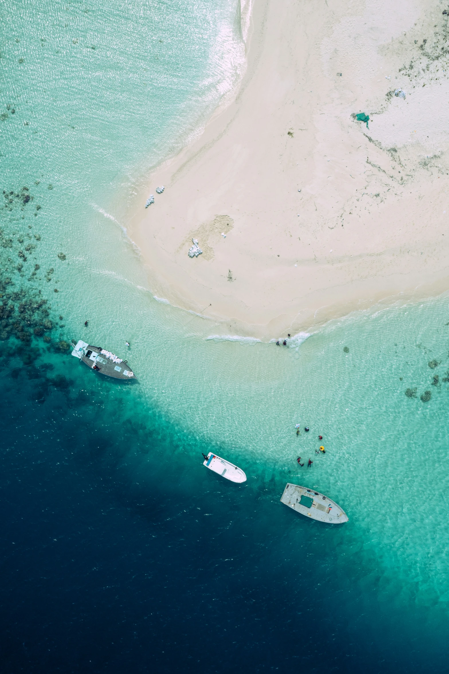 a sandy island is shown with three boats