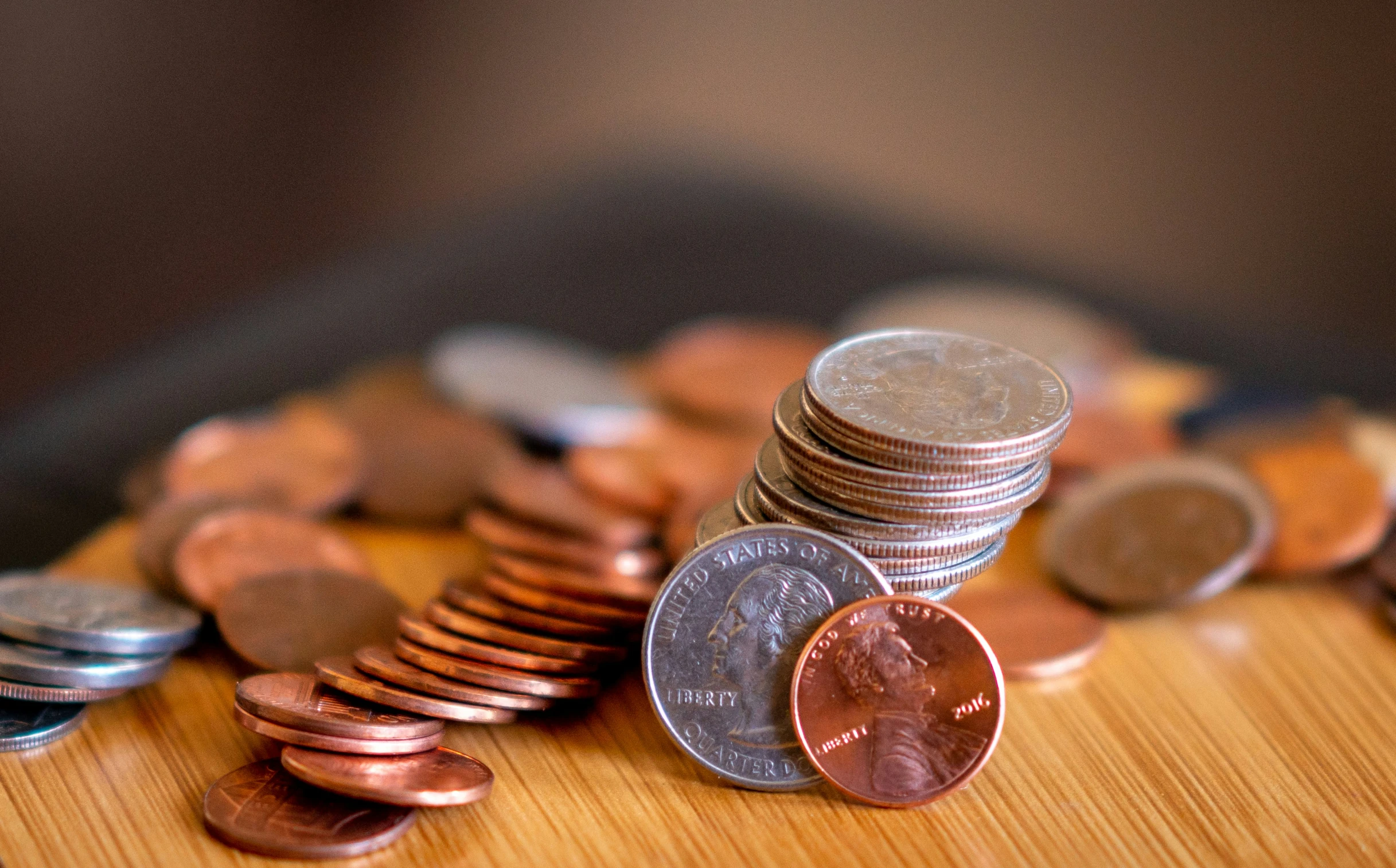 many different coins sitting on top of a wooden surface