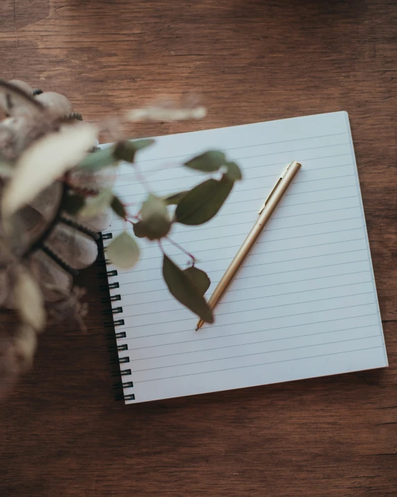 a note pad with a pen next to some flowers