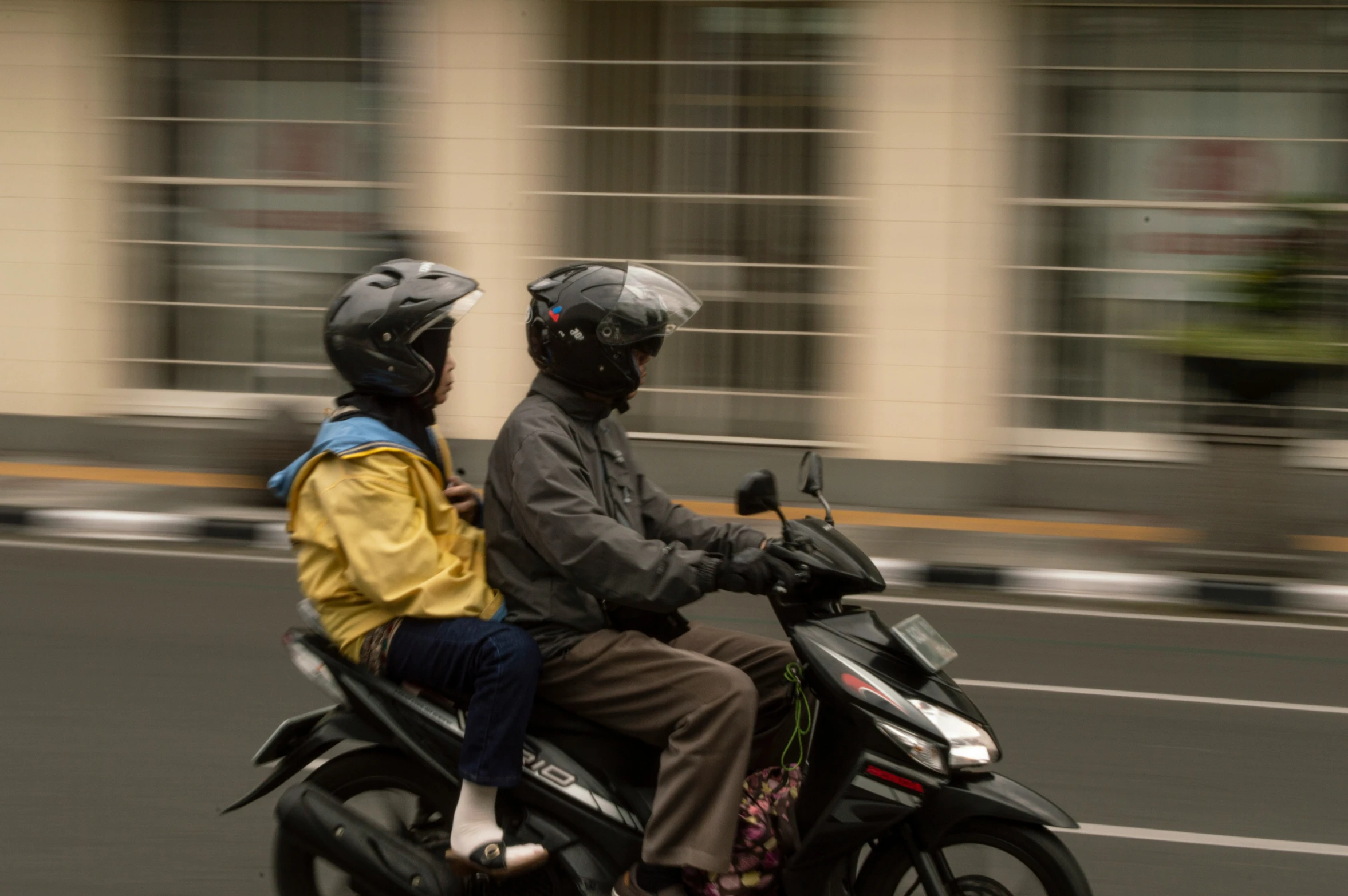 a man and woman riding a motorcycle down the road