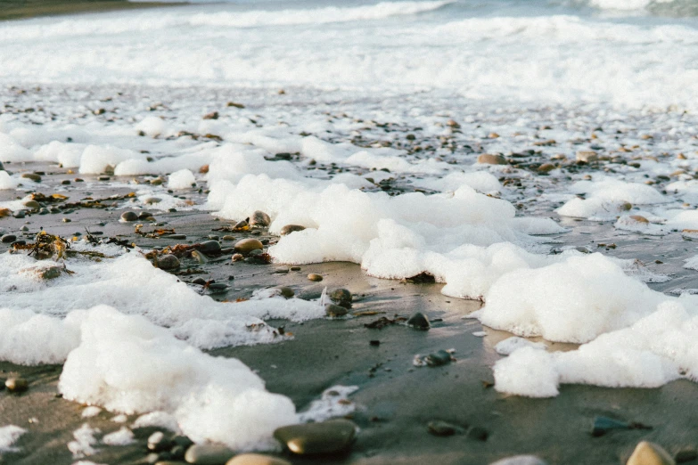 a group of pebbles covered in ice sitting on top of beach next to ocean