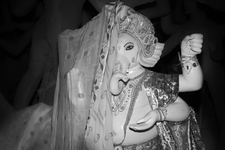 a figurine in a silver sari has a golden ring around her hand