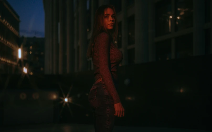 a woman in a tight dress standing outside a building at night