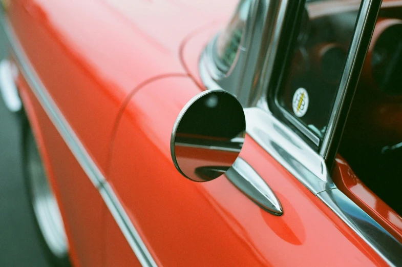 the back window of an old car with a round chrome fin