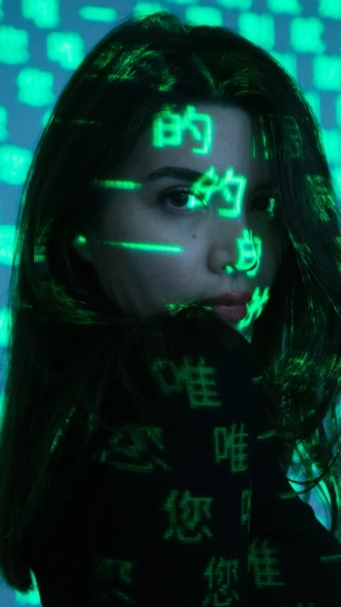 a woman in green light standing in front of a wall with squares on it