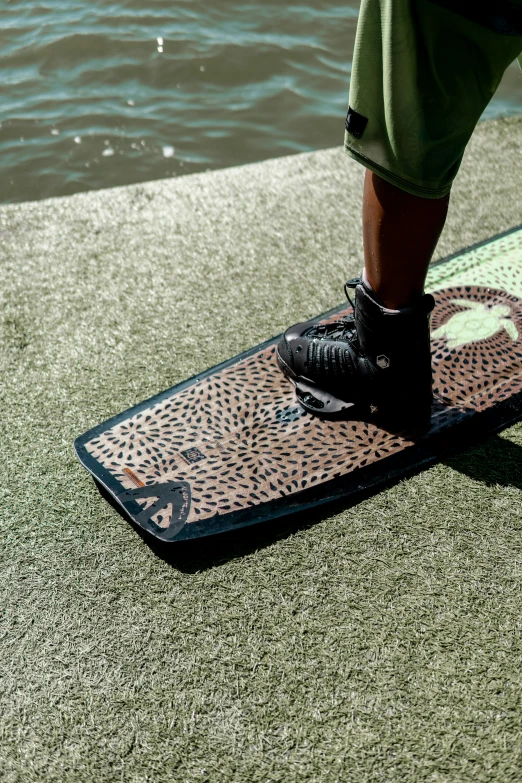 person's legs on a skateboard sitting by the water