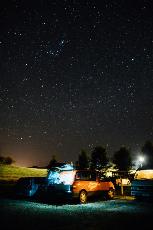 an orange truck parked at night in a field