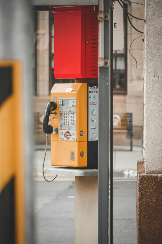 a red phone on the side of a yellow pole