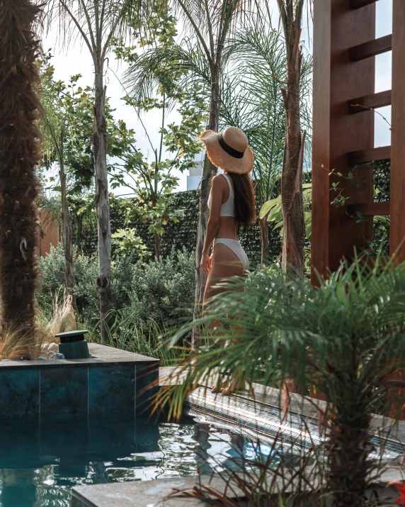 a woman with a straw hat next to a pool