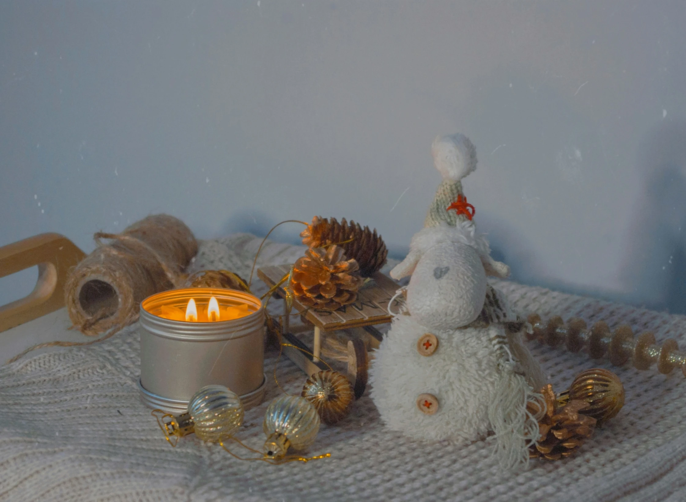 a small white teddy bear with lights next to a candle