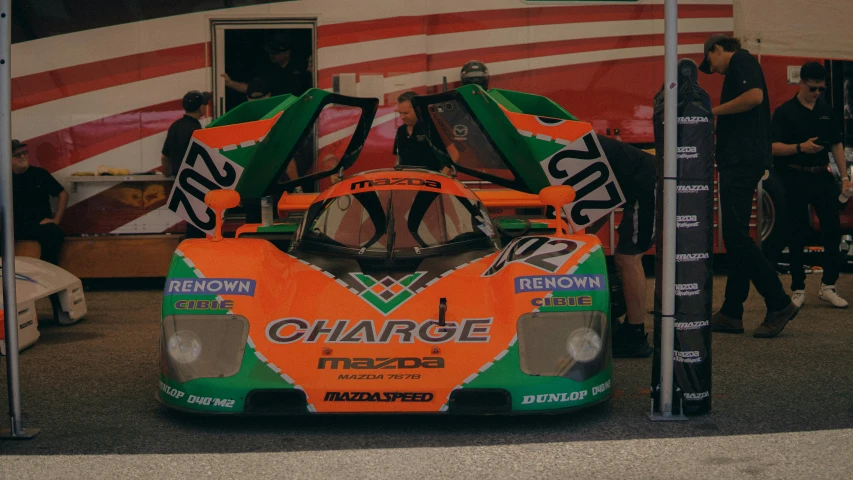 there is an orange and green racing car on display