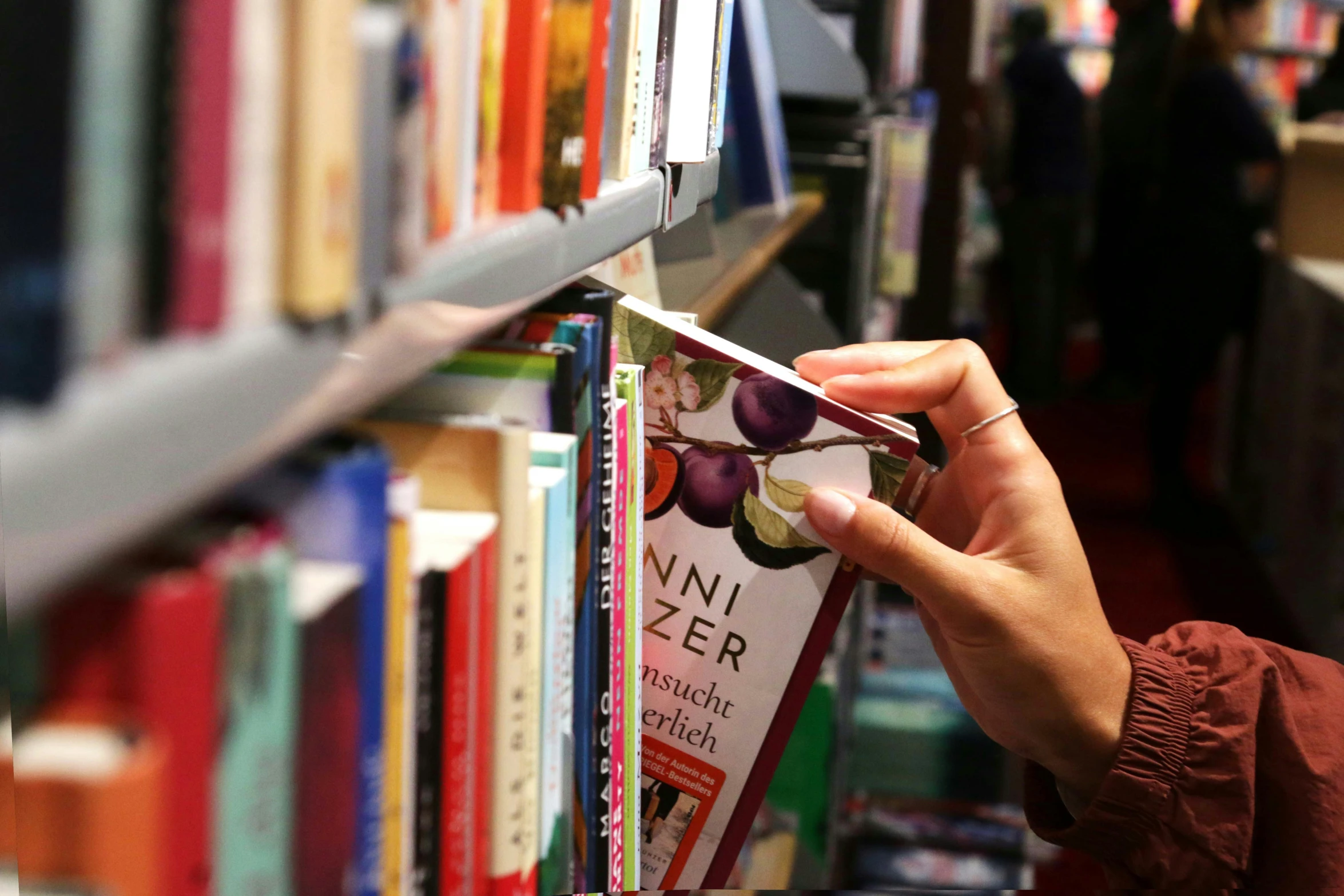 woman picking out some books from a shelf in the liry