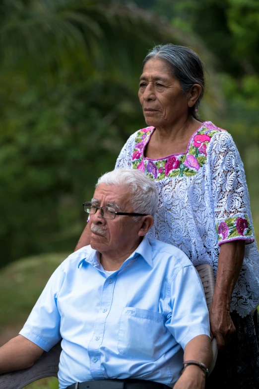 a woman in a chair stands beside a man