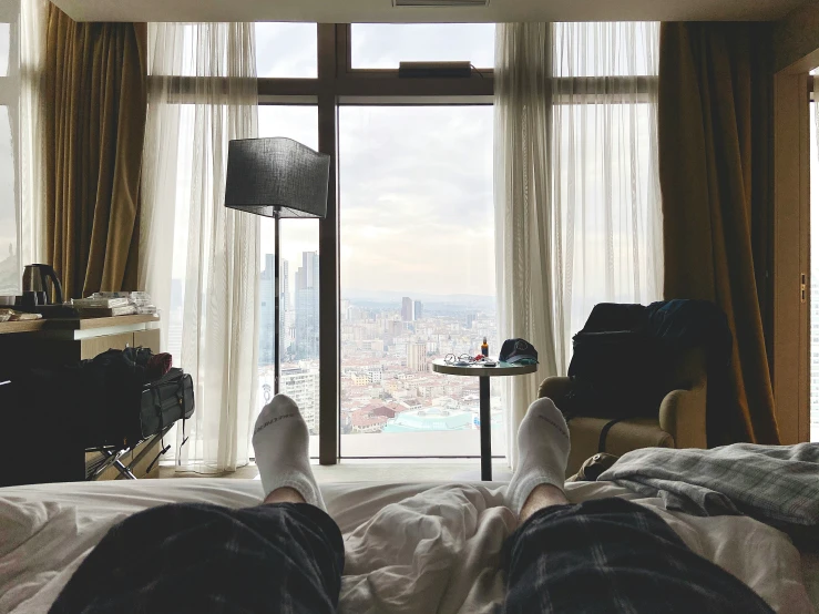 feet in bedroom overlooking city in daylight from window