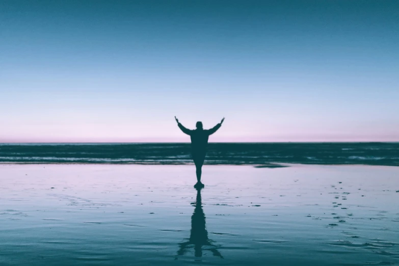 a person standing on the shore with their arms raised