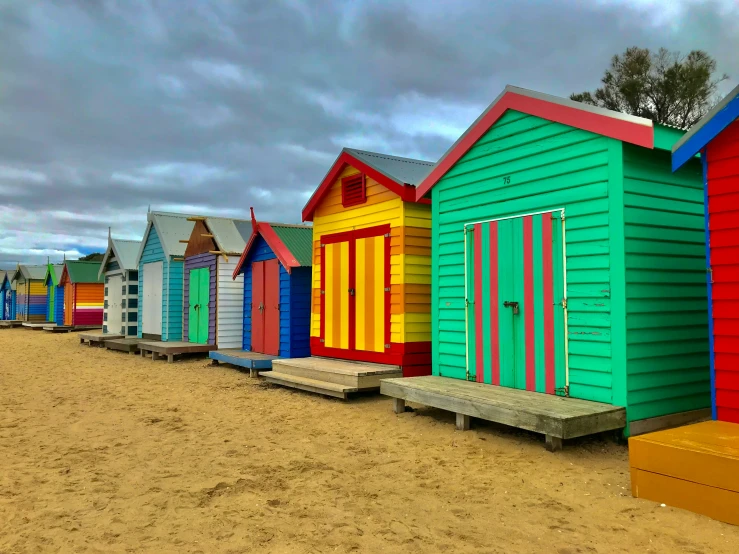 a row of small colorful beach huts on sand