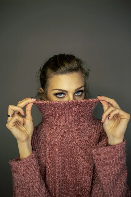 a woman holding up a red sweater over her face