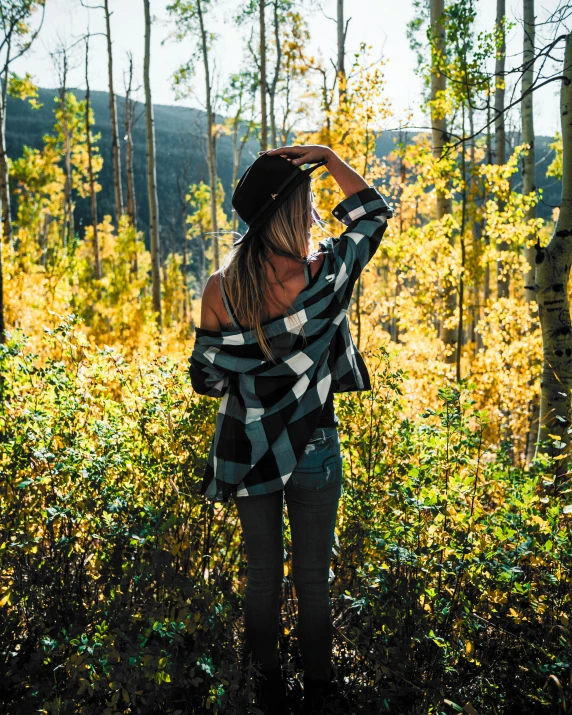 a woman in a checkered top looking out into the woods