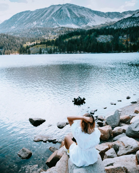 a woman sitting by the edge of a body of water