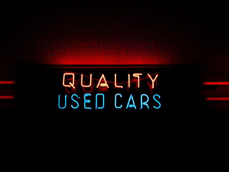the words quality used cars neon on a wall