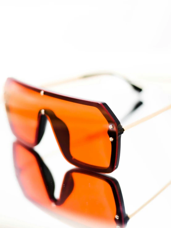 two pairs of orange sunglasses laying on a table