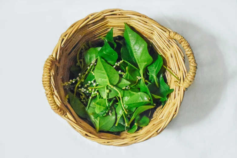 a basket of green leafy greens sitting on a white table cloth