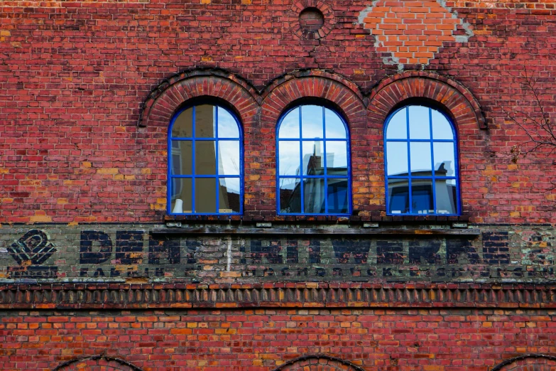 a brick building with three arched windows is red and blue